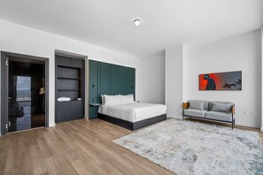 A modern bedroom with a bed, a grey sofa, a painting, and a wooden floor. - Exclusive 53rd Floor 2 Bedroom with Stunning Views E11EVEN Elite Amenities (Miami)