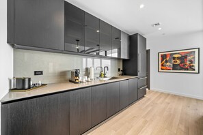 A modern kitchen with dark cabinetry, a countertop with a coffee machine, and a sink. - Exclusive 53rd Floor 2 Bedroom with Stunning Views E11EVEN Elite Amenities (Miami)