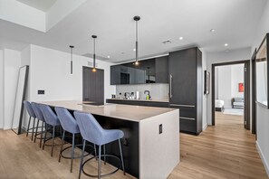 A modern kitchen with a central island, bar stools, pendant lighting, and dark cabinetry. - Exclusive 53rd Floor 2 Bedroom with Stunning Views E11EVEN Elite Amenities (Miami)