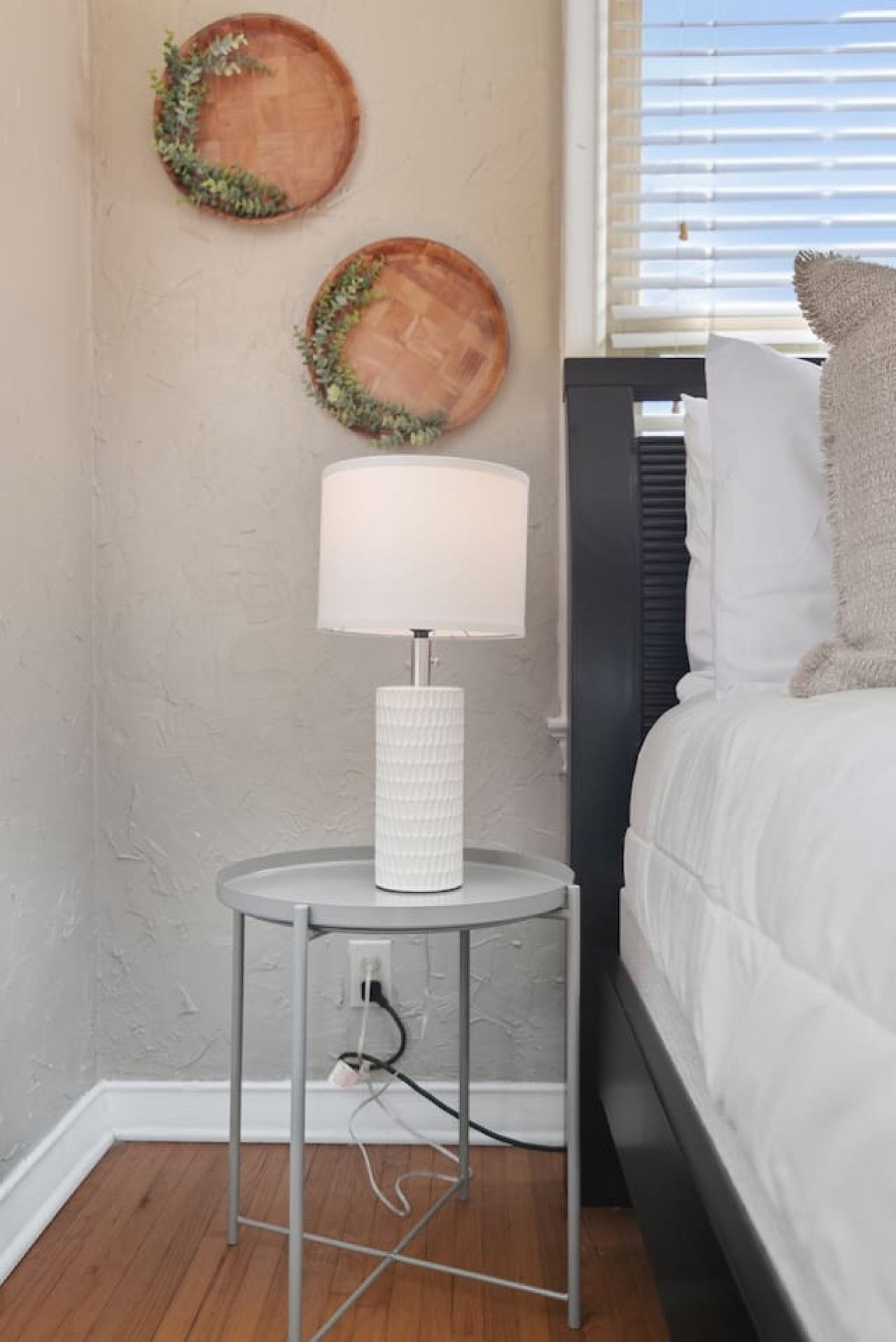 Une chambre à coucher avec un lit, une table de chevet avec une lampe et deux assiettes décoratives fixées au mur.