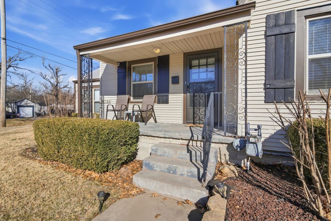 A residential house with a front porch, a garage, and a well-maintained lawn.