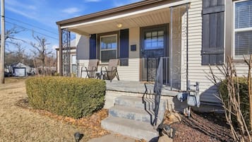 A residential house with a front porch, a garage, and a well-maintained lawn.
