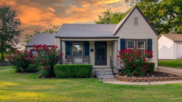 A single-story house with a front porch, a small garden with red flowers, and a clear sky. - The Corner Charmer• Near TU/Expo/Downtown (Tulsa)