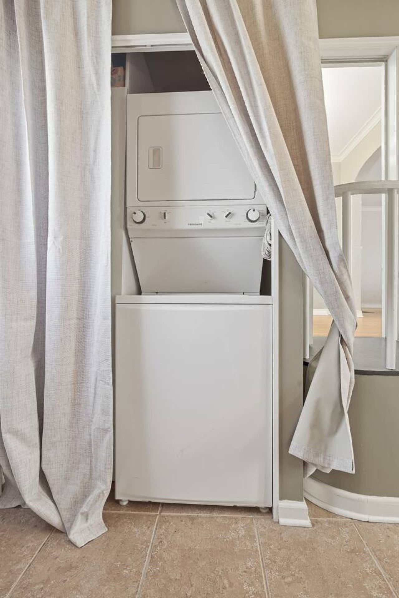 Une buanderie équipée d’un lave-linge et d’un sèche-linge, avec une porte et des rideaux.