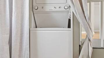 Une buanderie équipée d’un lave-linge et d’un sèche-linge, avec une porte et des rideaux.