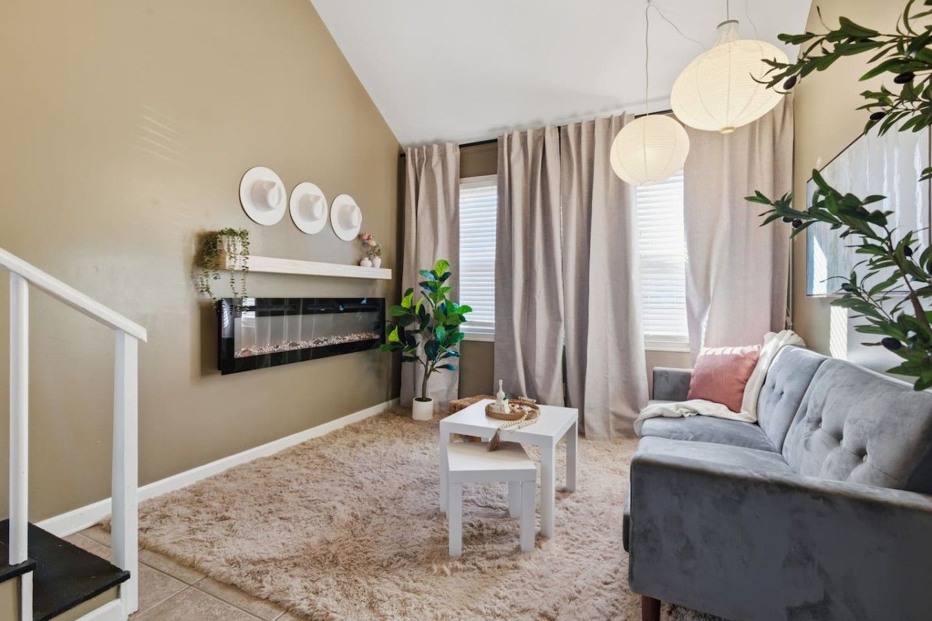 A living room with a fireplace, a grey sofa, a white coffee table, and a plant.