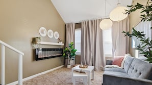 A living room with a fireplace, a grey sofa, a white coffee table, and a plant. - The Corner Charmer• Near TU/Expo/Downtown (Tulsa)