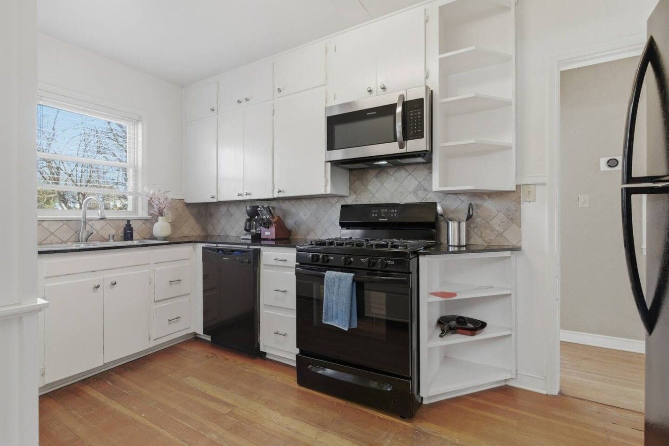 A kitchen with white cabinets, a black stove, a microwave, and a dishwasher.