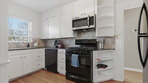 A kitchen with white cabinets, a black stove, a microwave, and a dishwasher. - The Corner Charmer• Near TU/Expo/Downtown (Tulsa)