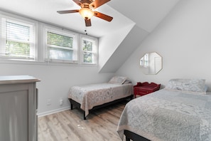 Ein Schlafzimmer mit zwei Betten, einem Deckenventilator und einem Fenster mit Jalousien.