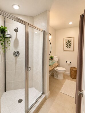 Un baño moderno con ducha envuelta en vidrio, inodoro y zona de lavamanos.