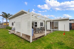 A single-story house with a covered patio area, a deck, and a fenced backyard. - Whanga on Foot - Brilliant Location (Whangamatā)