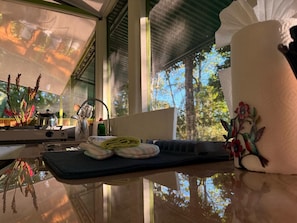 A kitchen counter with a kettle, a rolled-up towel, and a decorative item with a floral design.