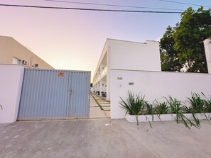 A gated entrance to a building with a white facade, a blue metal gate, and a number sign '940'. - Duplex Apartment 2 with 2 Suites 450m from the Beach in Santa Cruz Cabrália (Santa Cruz Cabrália)
