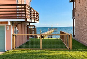Ein Küstenanwesen mit einer Holzdielen-Terrasse, Meerblick und einem eingezäunten Bereich mit Tor.