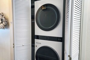 Máquina de lavar e secar empilhadas, com acabamento branco e porta preta.