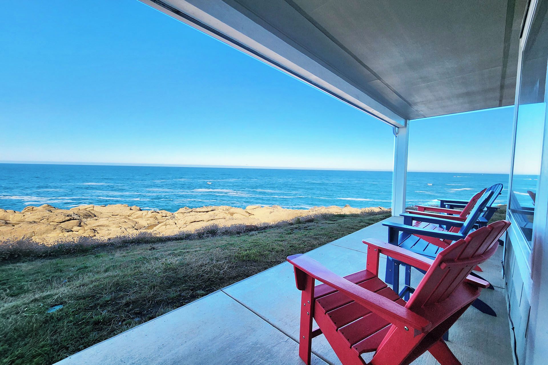 A covered outdoor seating area with a view of the ocean.