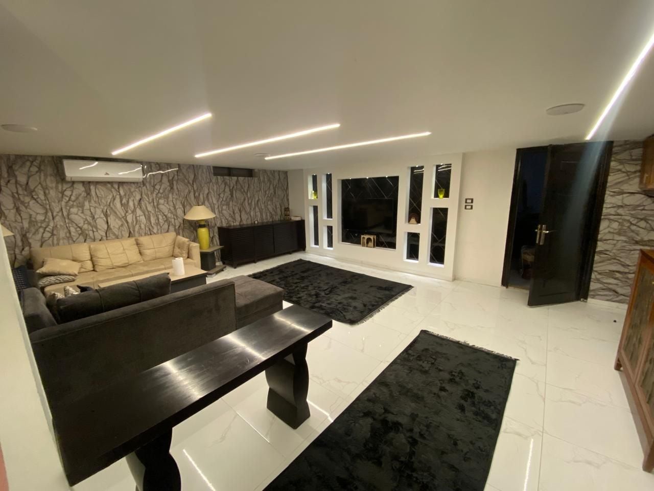 A modern living room with a sofa, a coffee table, and a black rug.