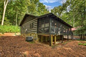 Eine Holzhütte mit einem großen Glasanbau, umgeben von einem Wald.