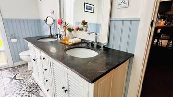 A bathroom with a large mirror, a sink, and a patterned floor.