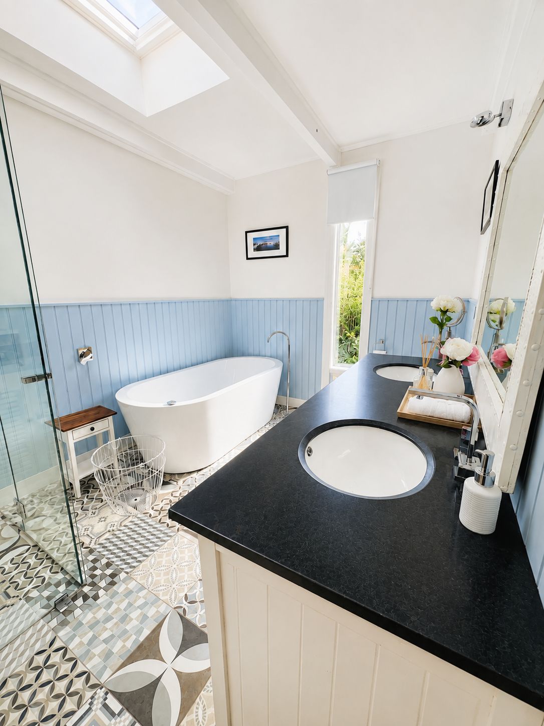 A modern bathroom with a freestanding bathtub, two sinks, and a glass shower enclosure.