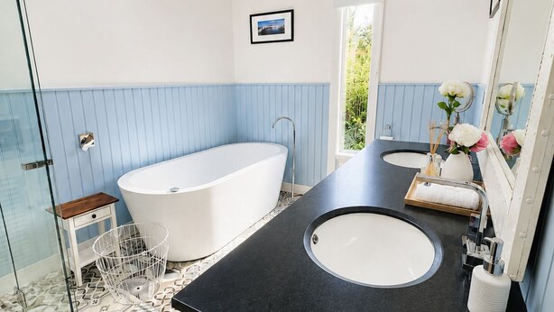Un bagno moderno con una vasca freestanding, due lavandini e un box doccia in vetro.