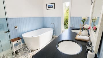 A modern bathroom with a freestanding bathtub, two sinks, and a glass shower enclosure.