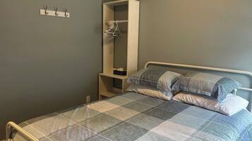 A bedroom with a bed, a wardrobe, and a coat rack.