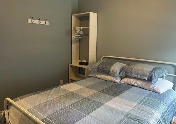 A bedroom with a bed, a wardrobe, and a coat rack.