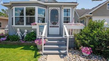 A two-story house with a front porch, a mailbox, and a number sign.