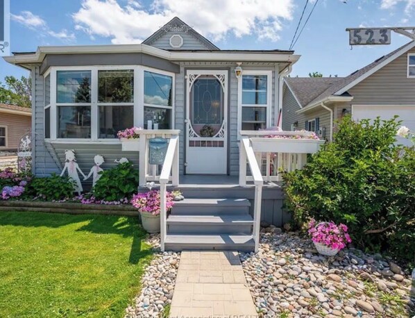A two-story house with a front porch, a mailbox, and a number sign.