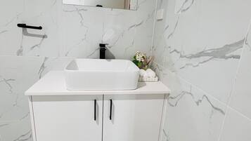 A bathroom with a white vanity, a mirror above the sink, and marble-patterned walls.