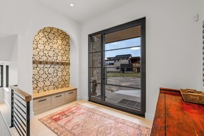 Ein modernes Interieur mit einer Steinsäule, einer großen Schiebeglaswand und einer Holzbank.