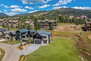 Un barrio residencial con casas modernas, un césped cuidado y montañas al fondo.
