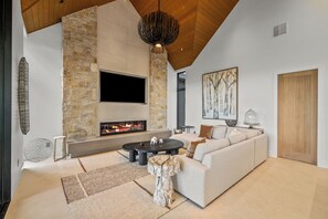 Una sala de estar moderna con chimenea de piedra, un televisor de pantalla plana grande, un sofá y una mesa de comedor.