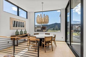 A modern dining area with a round table, wooden chairs, and a unique ceiling light. - French Point Ridge! Elegant, Brand New Single Family Home, Amazing! (Steamboat Springs)