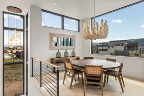 Un comedor moderno con una mesa redonda, sillas de madera y vistas al paisaje a través de amplios ventanales.
