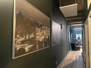 A corridor with a large black-and-white photograph of a bridge and buildings, a whiteboard, and a poster on the wall. - Cambridge Loft on Jasper Ave \| ICE District (Edmonton)