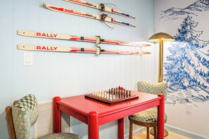 A dining area with a red table, chessboard, and skis mounted on the wall. - Wild & Well - Red Light • Sauna • Gym • Hot Tub (McGaheysville)