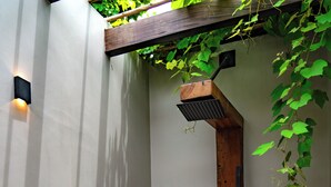 A modern shower area with a wooden structure, a stone bench, and a concrete floor. - Ahyiresu Farmhouse Resort (Aburi)