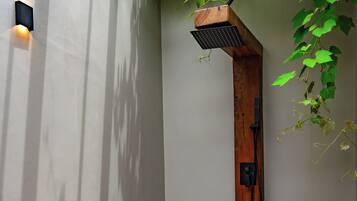 A modern shower area with a wooden structure, a stone bench, and a concrete floor.