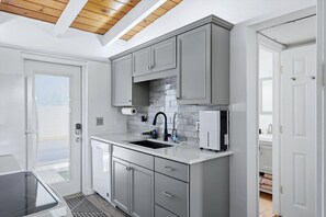 A modern kitchen with grey cabinets, a black faucet, and a white countertop. - Coastal Studio Retreat, Updated Kitchen/Bath, Private Beach, Casa Mar Resort (Sarasota)
