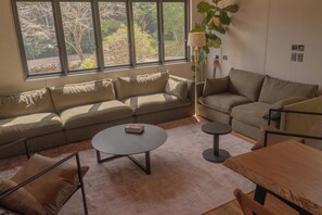 A living room with a sofa, a coffee table, a wooden table, and a lamp.