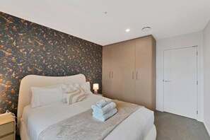 A bedroom with a bed, nightstands, a wardrobe, and a door. - Boutique CBD Apartment — Walk to Everything (Christchurch)