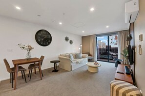 Un salon moderne comprenant un coin repas, un canapé, une table basse et un téléviseur.