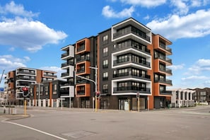 A multi-story residential building with balconies, a pedestrian crossing, and traffic lights. - Boutique CBD Apartment — Walk to Everything (Christchurch)