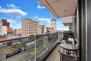 A balcony with a view of a city street, a table, and chairs. - Boutique CBD Apartment — Walk to Everything (Christchurch)