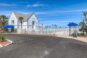 A white building with a gabled roof, a fenced pool area, and a covered seating area. - 2BR/2.5BA Gated Beachside Townhome (Cape Canaveral)