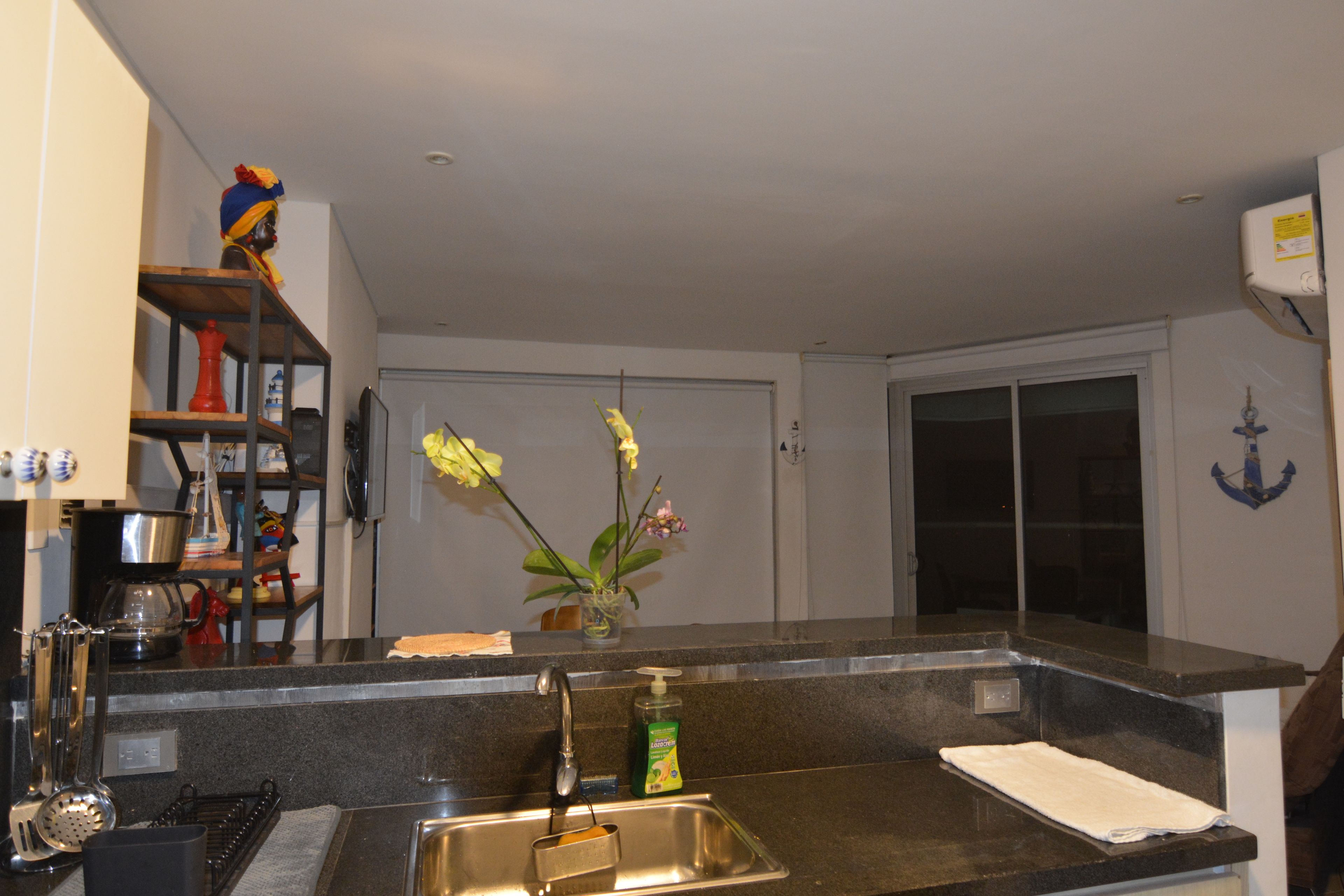 A kitchen with a stainless steel sink, a coffee maker, and a vase with flowers on the counter.