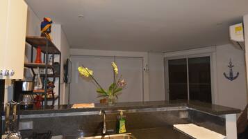 A kitchen with a stainless steel sink, a coffee maker, and a vase with flowers on the counter.